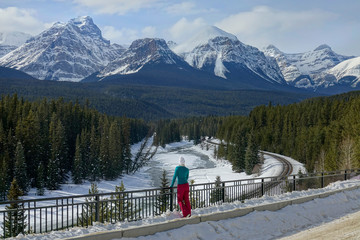Traveler exploring Alberta observes the breathtaking wintry mountains and woods