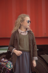 curly-haired blonde girl on the background of an orange truck with a big wheel, street style