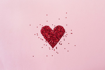 Heart symbol made of sparkles on pink background. Flat lay, top view Valentine's Day minimal...