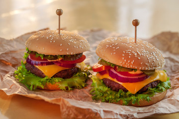 Meal, food. Two hamburger with cutlet grilled, lettuce, tomato, cheese, cucumber on a light wooden background.