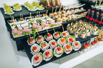 Buffet of different delicious food at a wedding celebration. Snacks for guests. Wedding party. Canapes, sushi, fruit, meat, drink, champagne, wine, juice.