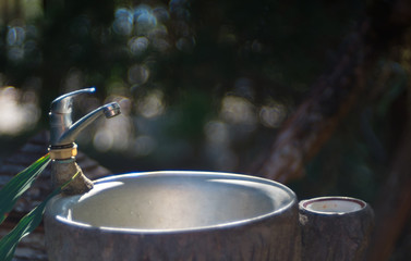 A tap water and aluminium sink (in a garden) with bubble blur background