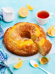 Lemon bundt cake with cup of tea. Blue background. Close up.