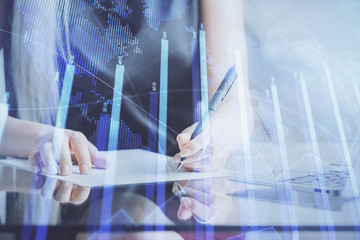 A woman hands writing information about stock market in notepad. Forex chart holograms in front. Concept of research.