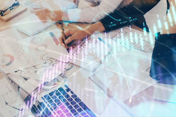 A woman hands writing information about stock market in notepad. Forex chart holograms in front. Concept of research. Double exposure