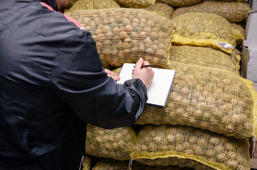 warehouse worker in a protective helmet and overalls checks the goods walnuts and dried fruits in...