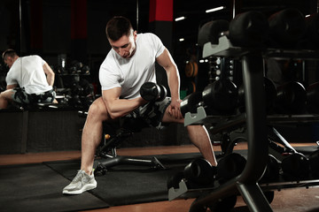 Fototapeta na wymiar Man working out with dumbbell in modern gym
