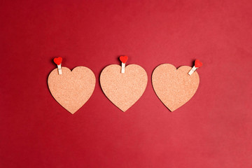 Cork hearts with clothespins and copy space on red background.