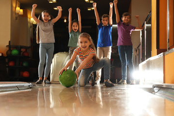 Girl throwing ball and spending time with friends in bowling club