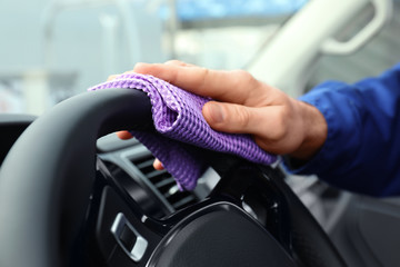 Car wash worker cleaning automobile interior, closeup