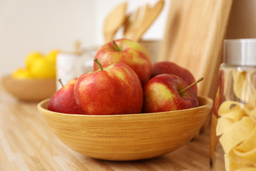 Apples in bowl on wooden countertop in kitchen. Interior element