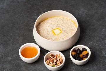 Oatmeal porridge with raisins, honey and nuts in a bowl