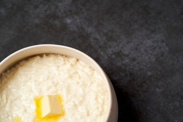 Rice porridge with milk, raisins, honey and nuts in a bowl.