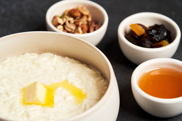 Rice porridge with milk, raisins, honey and nuts in a bowl.