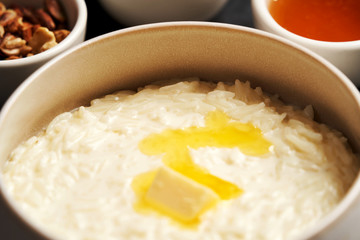 Rice porridge with milk, raisins, honey and nuts in a bowl.
