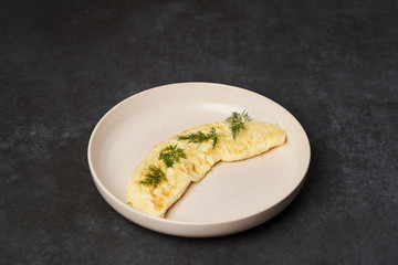 Traditional breakfast omelettes on a white plate on dark background