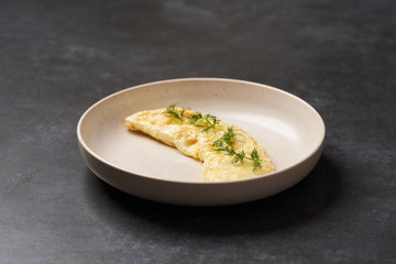 Traditional breakfast omelettes on a white plate on dark background