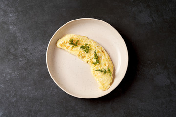 Traditional breakfast omelettes on a white plate on dark background