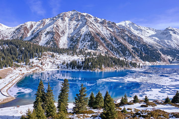 Autumn gives way to winter, air temperature drops and the water in the lake begins to freeze. Texture and patterns of ice on the serene water surface of a mountain lake; Big Almaty lake in Kazakhstan