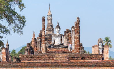 Tourist take pictures of ancient Buddha statue at sunrise in Ayutthaya, Thailand; travel and tourism concept