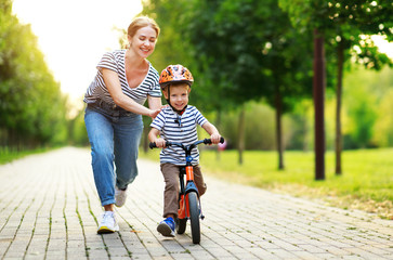 happy family mother teaches child son to ride a bike in the Park