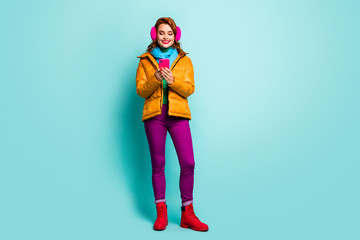 Full length photo of pretty traveler lady hold telephone searching map navigation wear trendy casual yellow overcoat scarf purple trousers shoes isolated teal color background