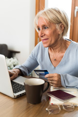 senior smiling woman buying on line with credit card vertical
