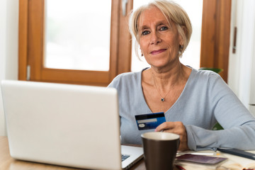 portrait of a woman with laptop in kitchen doing shopping online