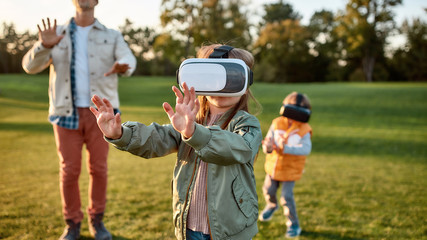 Digital weekend. Family playing in virtual reality glasses outdoors