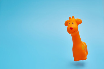 Toy giraffe flying in the air on a blue background. Levitation and minimalism. Modern greeting card or banner with copyspace.