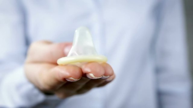 Female fingers holding condom, sexually transmitted diseases, protection