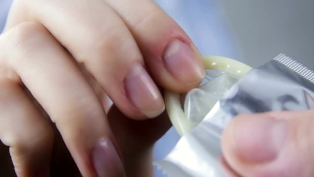 Close-up of the hand of a girl pulling out a condom.