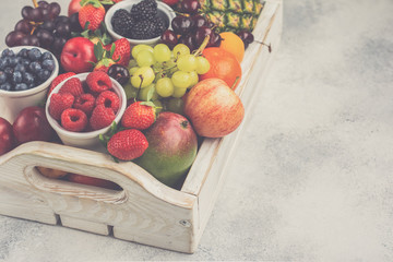 Healthy fruit in a tray filled with strawberries raspberries oranges plums apples kiwis grapes blueberries, top view, selective focus