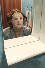 European woman apply face mask on face at bathroom
