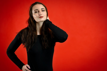 Photo of a pretty young brunette woman with a smile with good makeup on a red background. Concept girl talking in front of the camera with emotions.