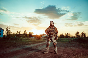 Fototapeta premium American soldier with the M4 rifle on the ruined town background.