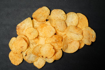 Crispy potato chips on dark