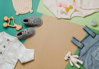 Baby clothes and shoes on neutral background with copy space