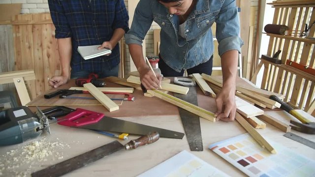 Young Asian group man worker measuring wood plank for build diy wood furniture in workshop