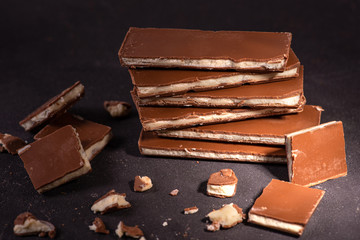 Pieces of chocolate with a mint layer  lie on a dark texture surface