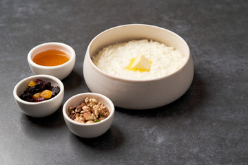 Rice porridge with milk, raisins, honey and nuts in a bowl.