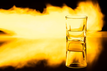 Kielszek z whisky na tle płomieni ognia z efektem odbicia © andsko