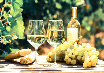 still life with glass of White wine grapes and bread on table in field