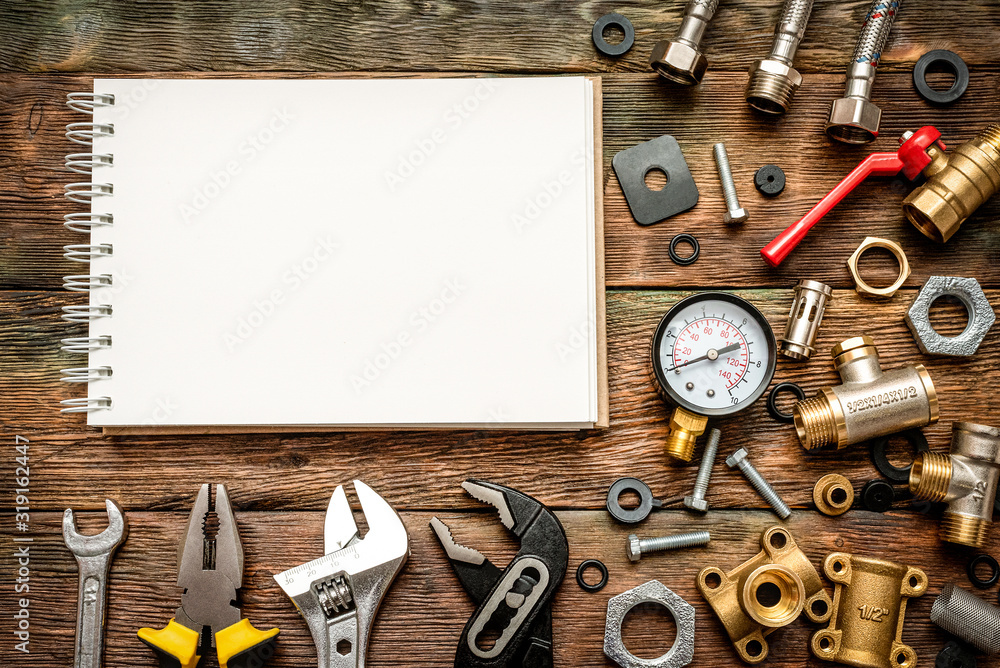 Wall mural Plumbing flat lay background with copy space. Work tools, pipeline equipment and blank page notepad on plumber workbench. Fix list mockup.