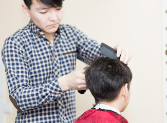 Obraz premium hairdresser cuts client's hair. Rear view of man in the barber shop.