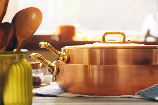 Copper cookware with wooden kitchen utensils close up