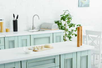 flour in glass bowl near raw dumplings in modern kitchen