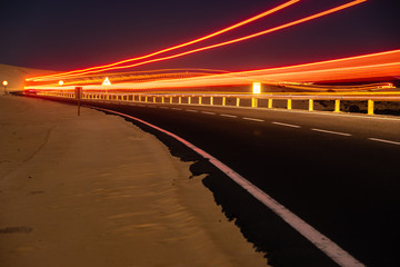 asphalt road running through the sandy desert at night