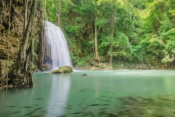 Beautiful silky water flowing on cliff rock around with blue-green water and green forest background, Erawan waterfalls 3th step, Kanchanaburi, west of Thailand.