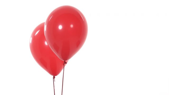Close-up of two red flying balloons. Objects moving from left to right. Isolated, on white background. Copy space